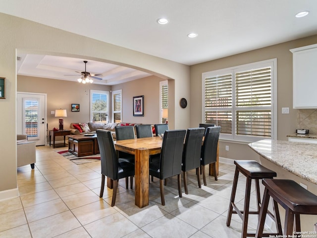 tiled dining room featuring ceiling fan and a tray ceiling