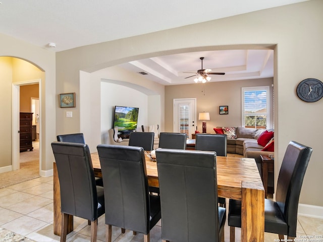 tiled dining area featuring ceiling fan and a tray ceiling