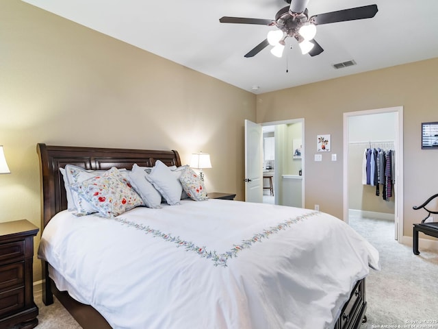 bedroom with ceiling fan, a walk in closet, a closet, and light carpet