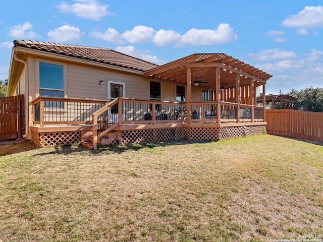 rear view of house featuring ceiling fan, a yard, and a deck