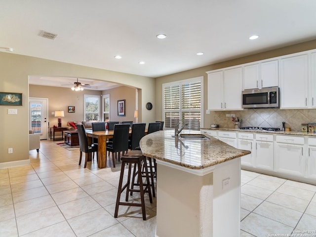 kitchen featuring sink, light stone counters, a center island with sink, appliances with stainless steel finishes, and white cabinets