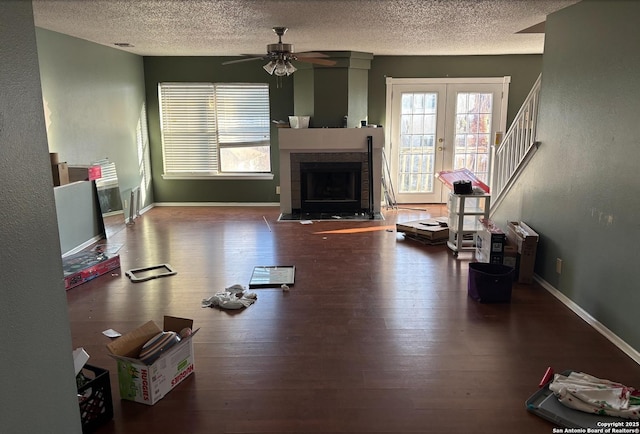 living room featuring hardwood / wood-style flooring, a textured ceiling, a tile fireplace, and french doors