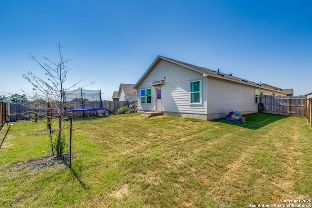 back of property with a yard and a trampoline