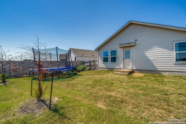 back of house with a trampoline and a lawn