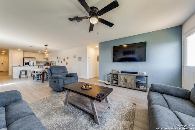 living room with ceiling fan and light hardwood / wood-style flooring