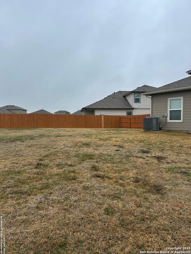 view of yard with central AC and fence
