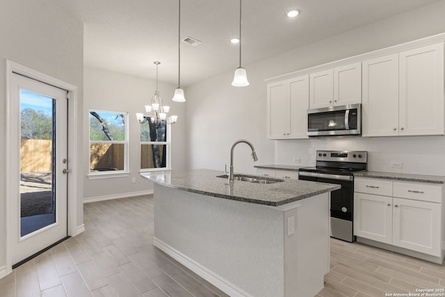 kitchen with pendant lighting, sink, white cabinetry, stainless steel appliances, and an island with sink