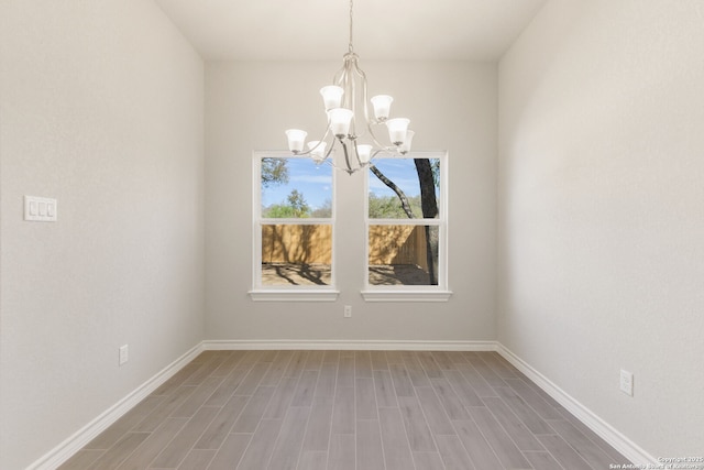 unfurnished dining area featuring an inviting chandelier and hardwood / wood-style floors