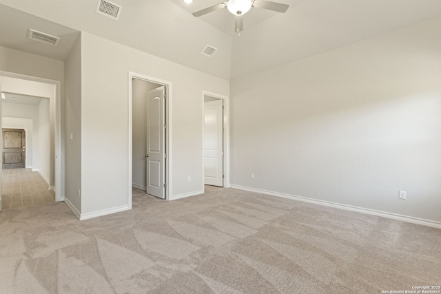 unfurnished bedroom with vaulted ceiling, a walk in closet, light colored carpet, and ceiling fan