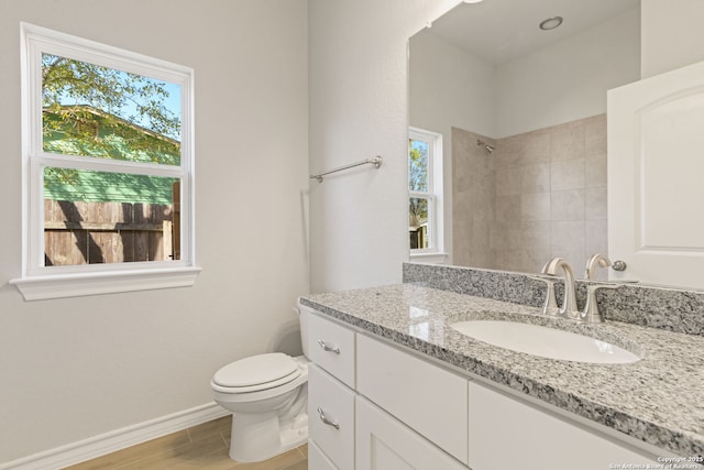 bathroom featuring vanity, hardwood / wood-style flooring, toilet, and tiled shower