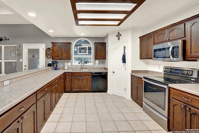 kitchen featuring sink, light tile patterned floors, kitchen peninsula, and appliances with stainless steel finishes