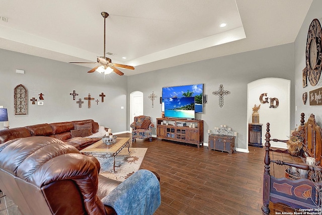 living room featuring ceiling fan, dark hardwood / wood-style floors, and a raised ceiling