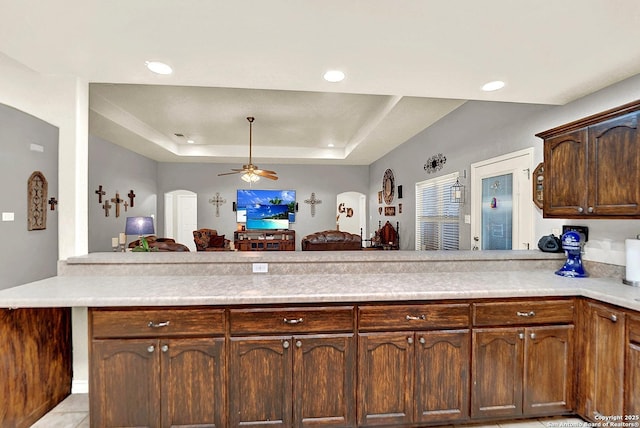 kitchen featuring a tray ceiling, ceiling fan, and kitchen peninsula