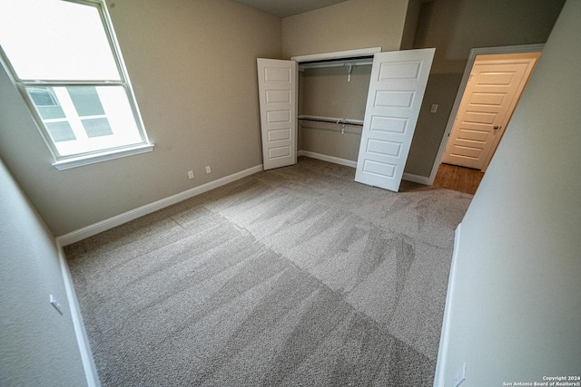 unfurnished bedroom featuring light carpet and a closet