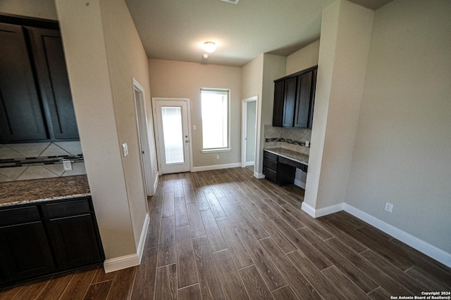 kitchen with dark wood-type flooring, stone countertops, and tasteful backsplash