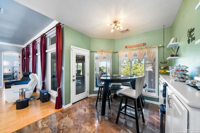 dining room featuring visible vents, baseboards, and a textured ceiling