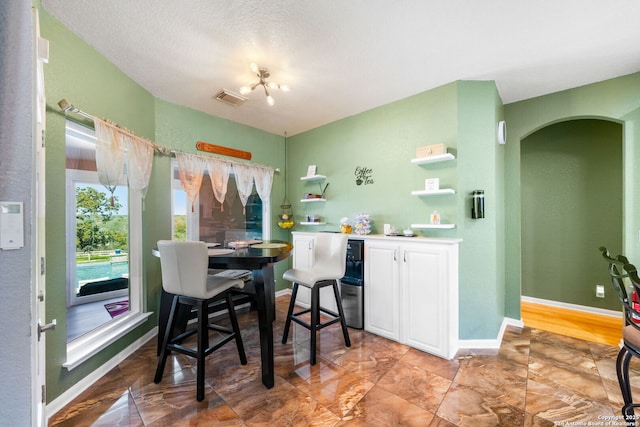 dining room with arched walkways, visible vents, and baseboards