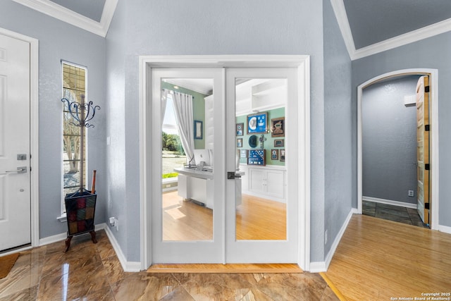 entryway featuring ornamental molding, arched walkways, a textured wall, and baseboards