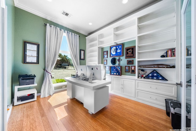 office with built in shelves, visible vents, baseboards, light wood-type flooring, and crown molding