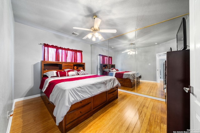 bedroom featuring ceiling fan, light wood finished floors, visible vents, and baseboards