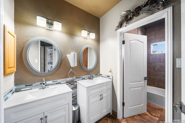 bathroom with two vanities, a sink, and a textured wall