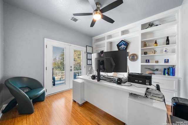 home office featuring visible vents, ceiling fan, french doors, light wood-style floors, and built in shelves