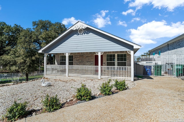 view of front of home with fence, a porch, and brick siding