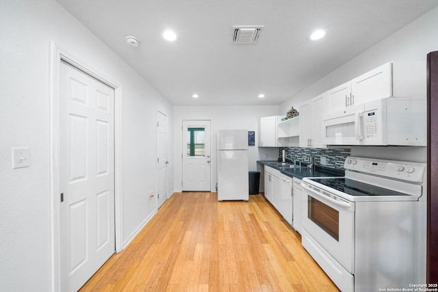 kitchen featuring white appliances, visible vents, white cabinets, dark countertops, and light wood-type flooring