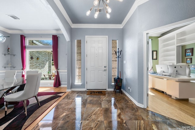 foyer with marble finish floor, crown molding, baseboards, and a notable chandelier