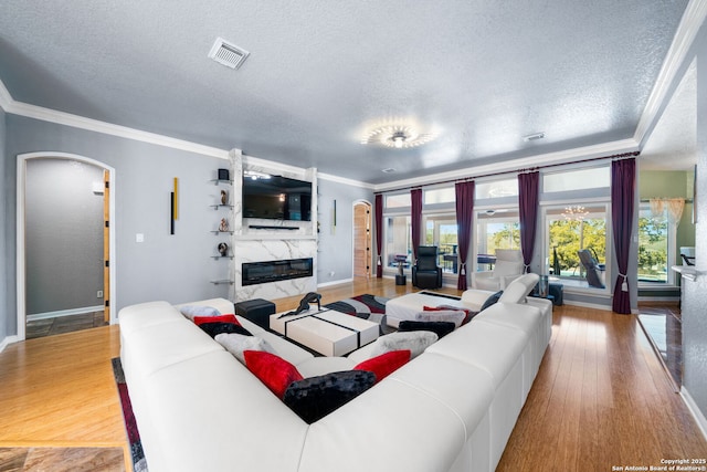 living room featuring arched walkways, a fireplace, wood finished floors, and visible vents