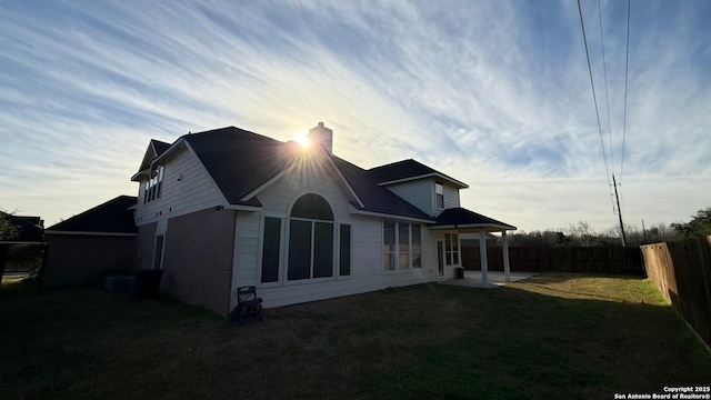 back house at dusk with a yard and a patio