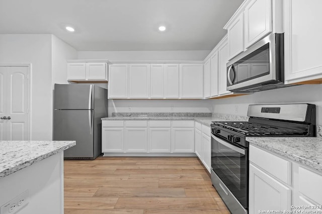 kitchen featuring light stone countertops, stainless steel appliances, and white cabinets