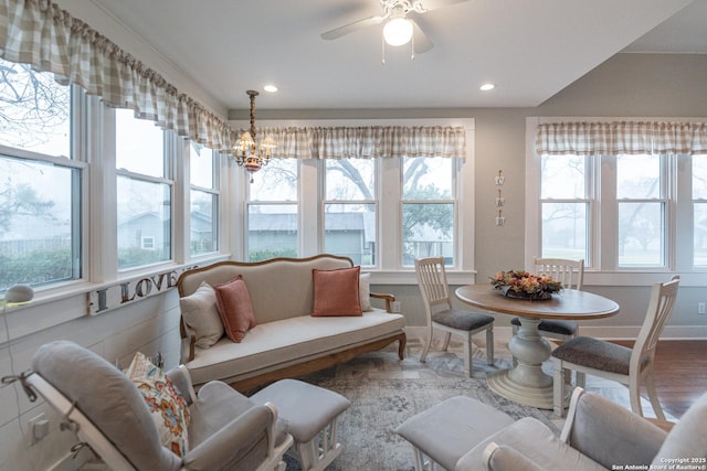 sunroom / solarium with ceiling fan with notable chandelier and a wealth of natural light