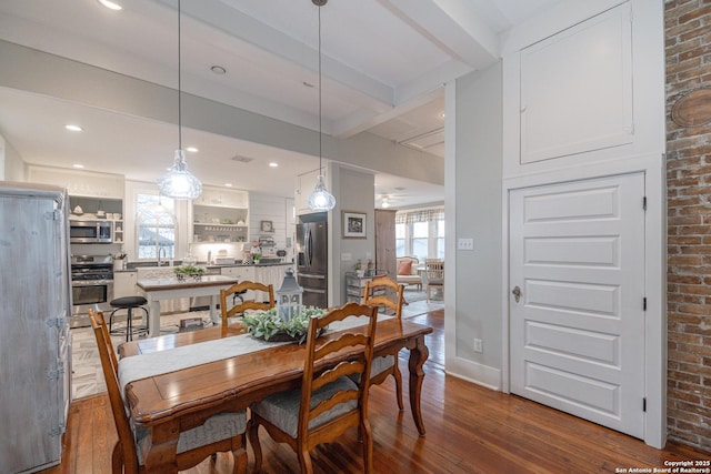 dining area featuring hardwood / wood-style flooring, sink, and beam ceiling