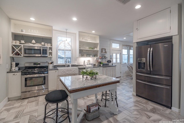 kitchen with pendant lighting, stainless steel appliances, and white cabinets