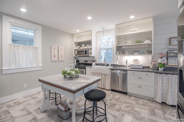 kitchen featuring white cabinetry, decorative light fixtures, and stainless steel appliances