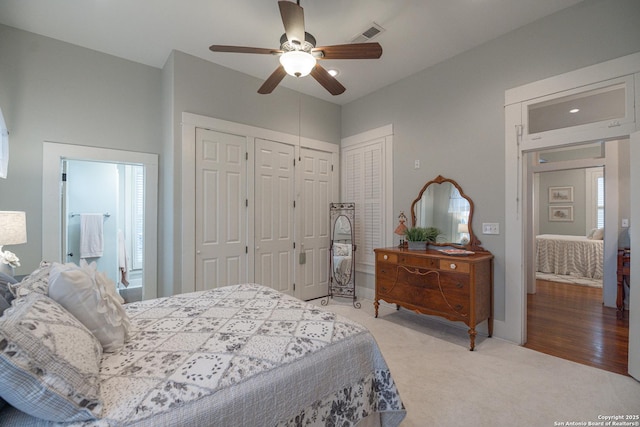 bedroom with two closets, carpet floors, and ceiling fan