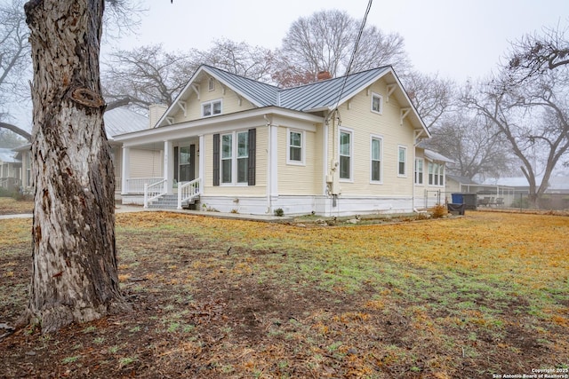 view of side of home featuring a porch and a lawn