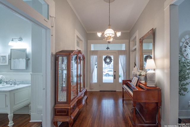 foyer with ornamental molding, dark hardwood / wood-style floors, sink, and a notable chandelier