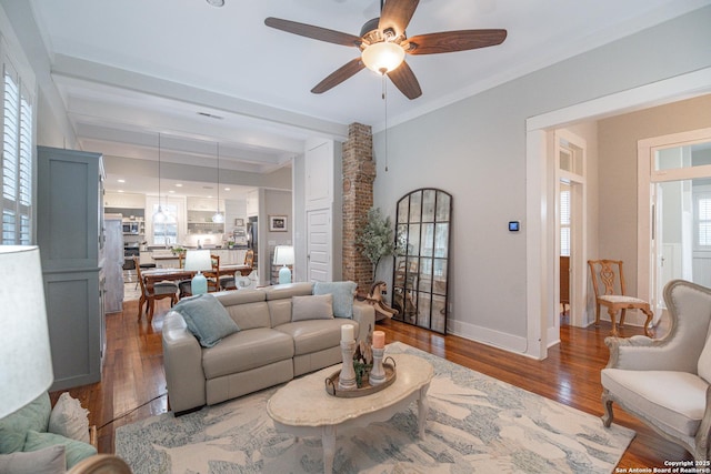 living room featuring ceiling fan, dark hardwood / wood-style flooring, and beam ceiling