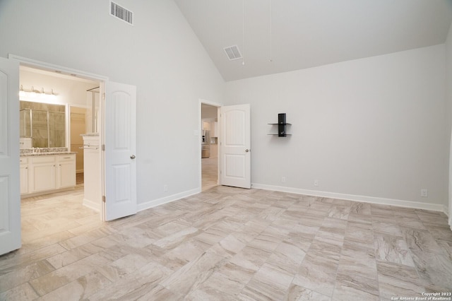 unfurnished bedroom with high vaulted ceiling and ensuite bath