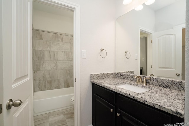 full bathroom with vanity, tiled shower / bath, and toilet