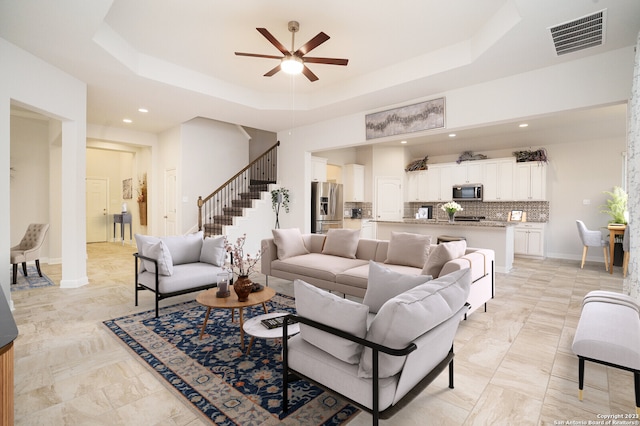 living room featuring a raised ceiling and ceiling fan