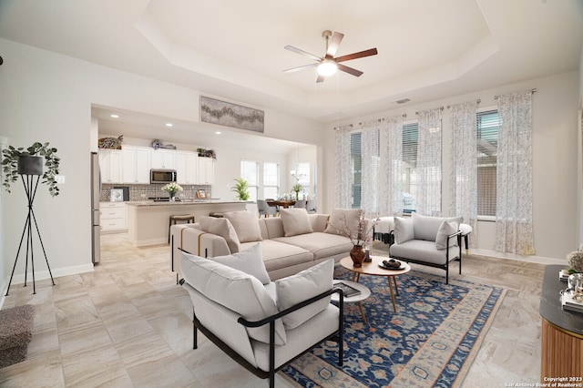 living room featuring ceiling fan and a tray ceiling