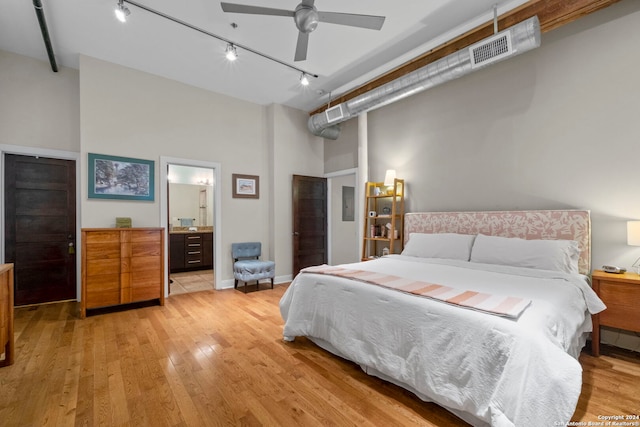 bedroom with connected bathroom, light wood-type flooring, track lighting, a towering ceiling, and ceiling fan