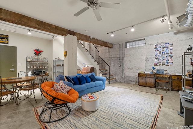 living room with ceiling fan, a fireplace, rail lighting, and beamed ceiling