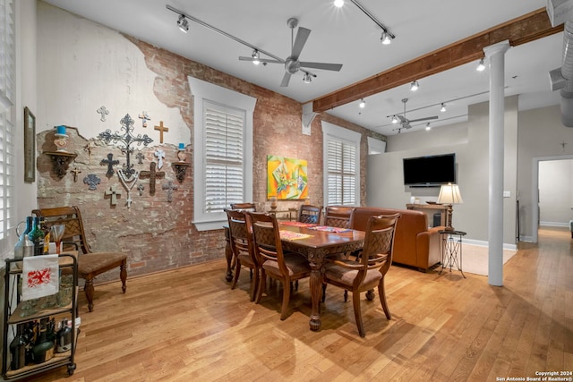 dining area with rail lighting, ceiling fan, light hardwood / wood-style floors, brick wall, and beamed ceiling