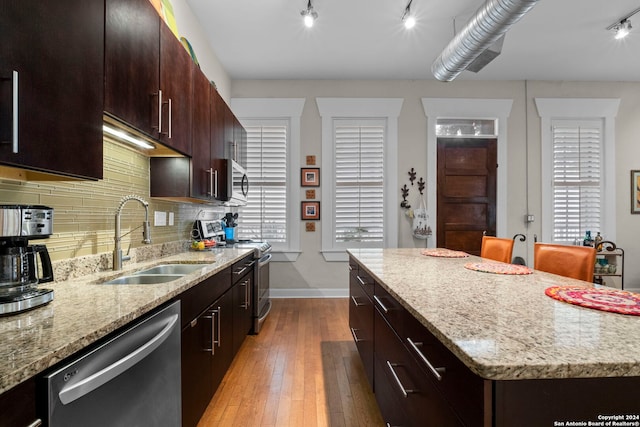 kitchen with a kitchen island, sink, decorative backsplash, stainless steel appliances, and light stone countertops