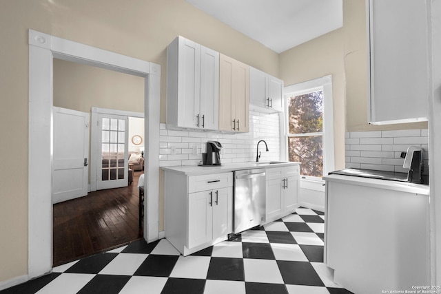 kitchen featuring stainless steel dishwasher, a healthy amount of sunlight, and white cabinets