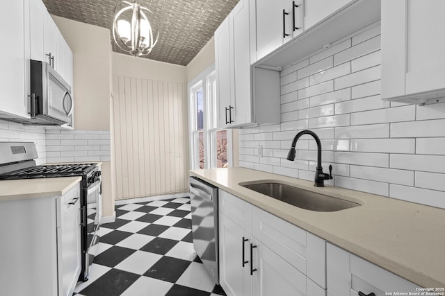 kitchen featuring appliances with stainless steel finishes, sink, hanging light fixtures, and white cabinets